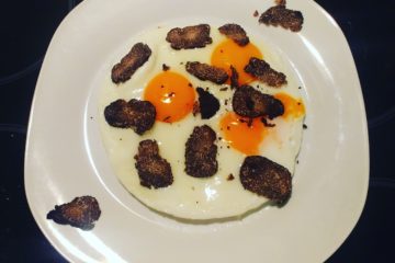 Uova al tegamino con fonduta cremosa di taleggio e scaglie di Tartufo Nero Pregiato, un antipasto raffinato e saporito